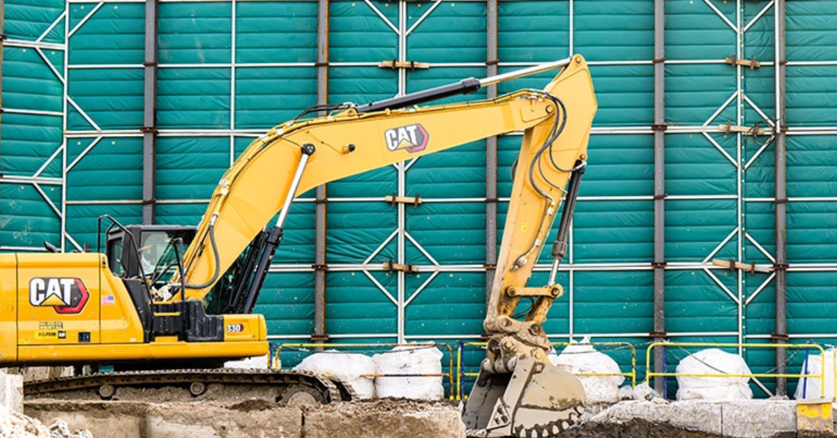 Excavator by a noise barrier. 